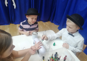 chłopcy malują dziewczynce paznokcie